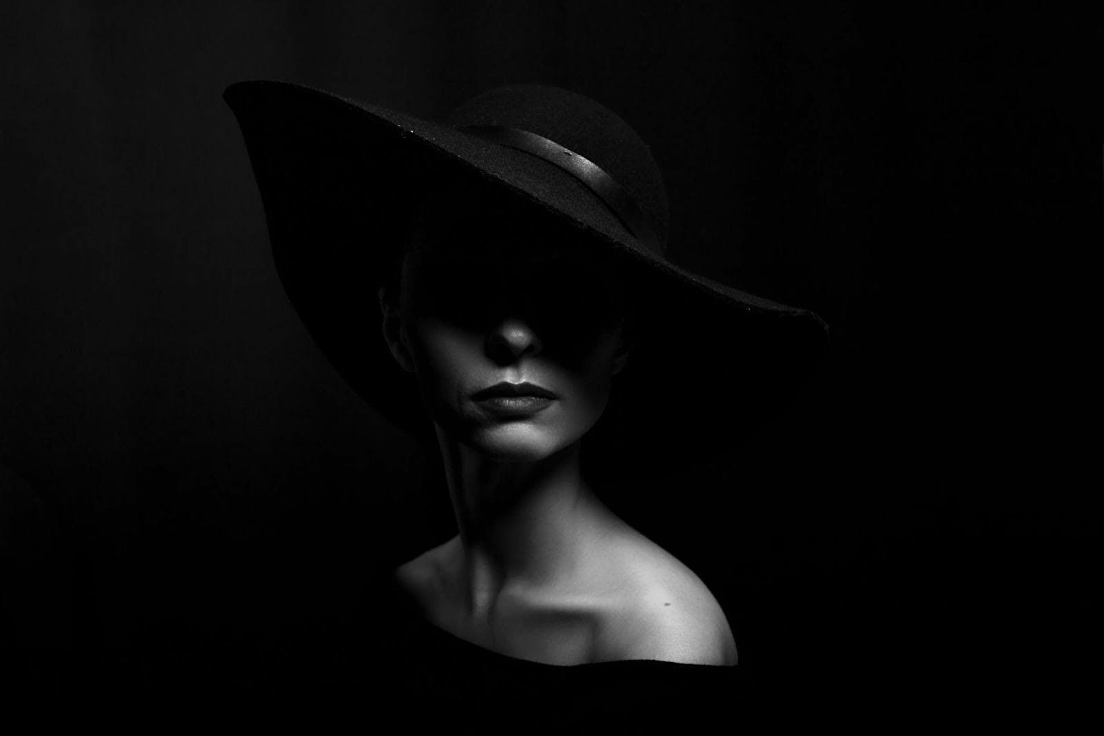 A black and white portrait of a woman in a hat, highlighting her elegance and timeless beauty