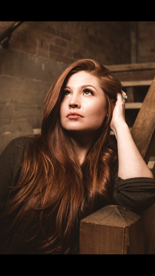 A woman with flowing red hair on a rustic staircase creates a serene atmosphere