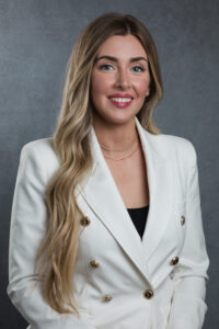 A woman dressed in a stylish white blazer paired with a black top, showcasing a modern and elegant look.