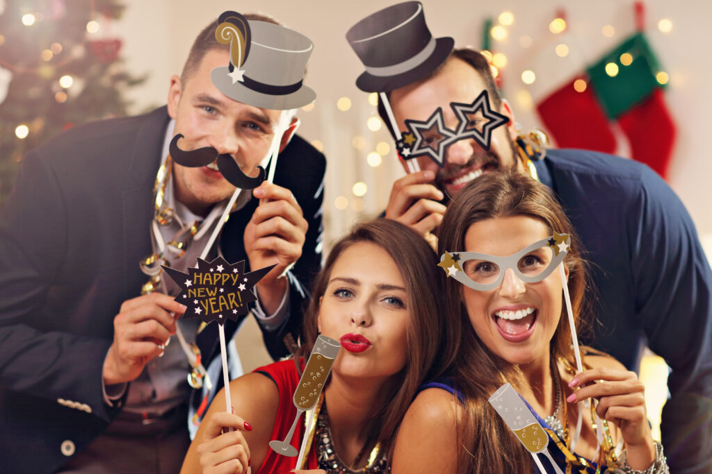 A group of coworkers in with props in a holiday party setting.