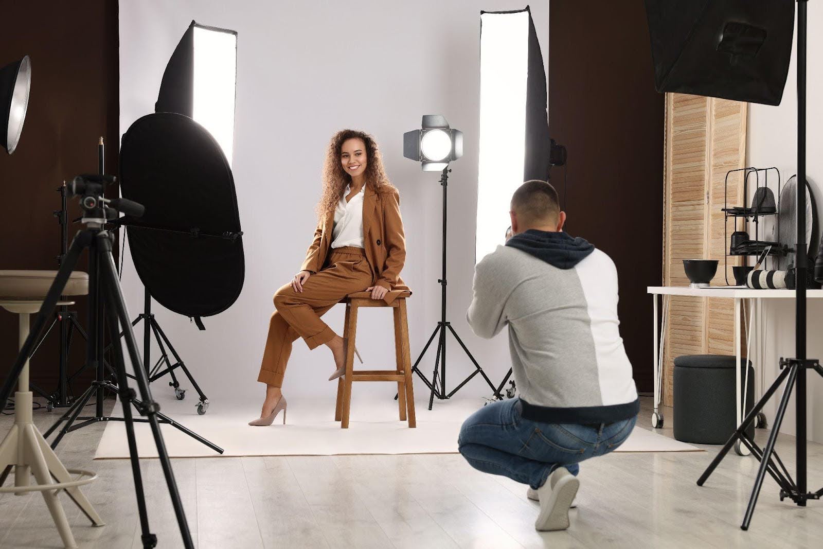 A man captures a photograph of a woman posing in a well-lit studio environment