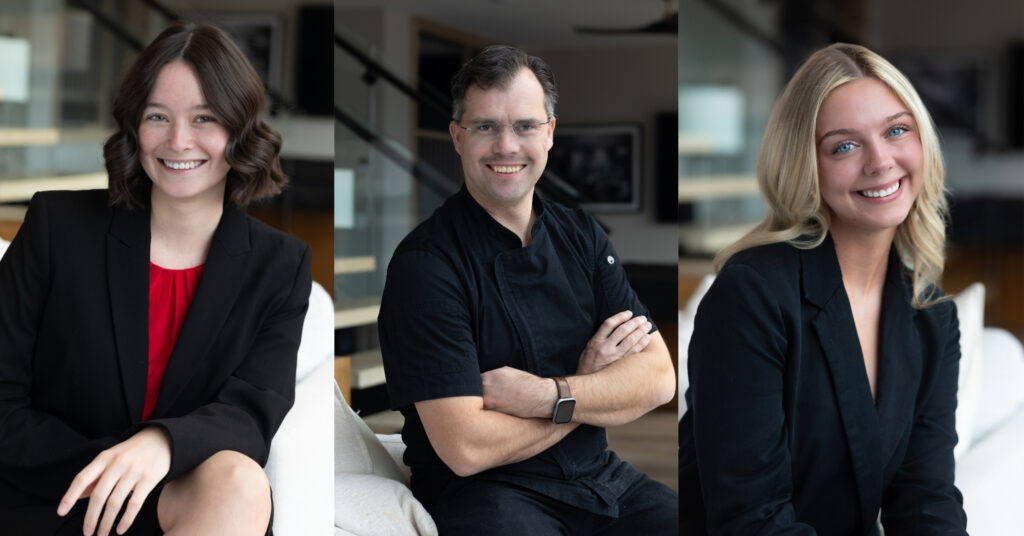 Three business people, dressed professionally, smile for the camera,