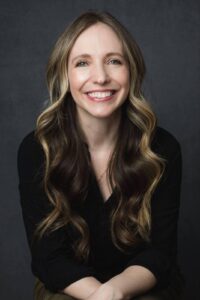 A woman with long hair dressed in a black shirt posing confidently