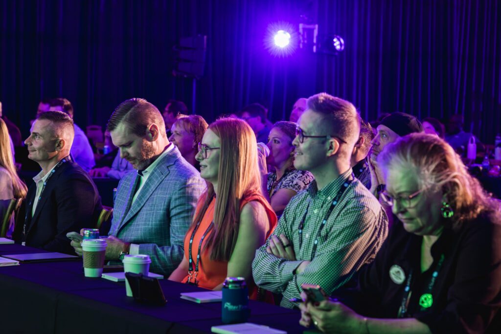 Conference attendees with lanyards watching a keynote session in Utah